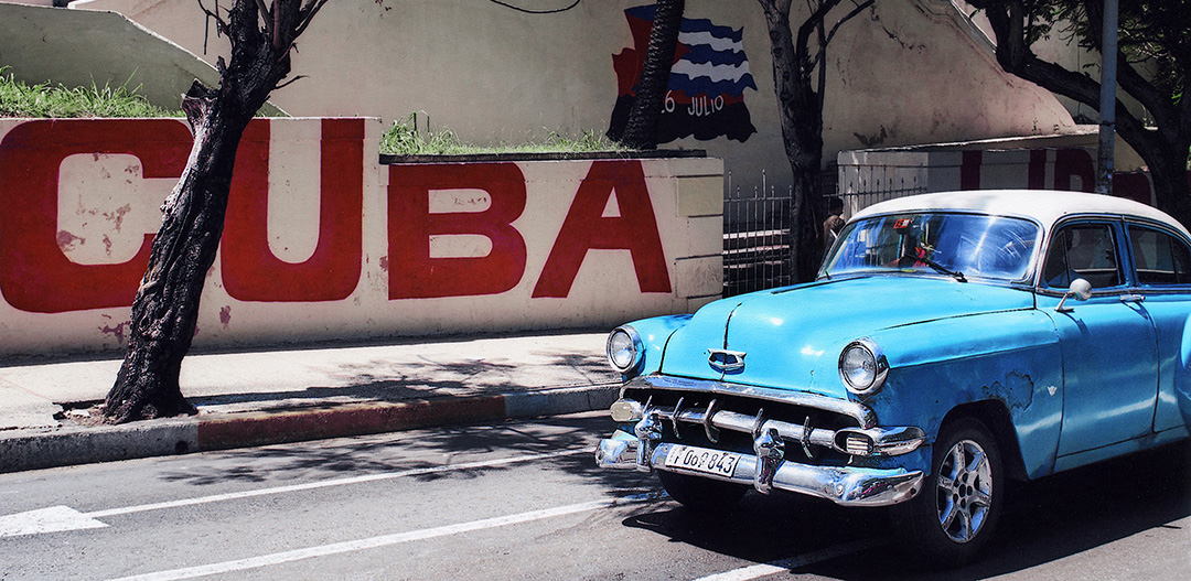 Blue car in front of mural
